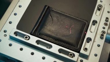 Preparing to start process of laser engraving of coat of arms of Ukraine,trident pattern,close-up,top view. Chaotic flickering of laser on black business card holder surface according to sketch.
