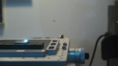 Camera passage in front of working platform of laser machine with object lying on it in process of engraving with laser beam movement. Interior of engraving workshop, close up surface, side view