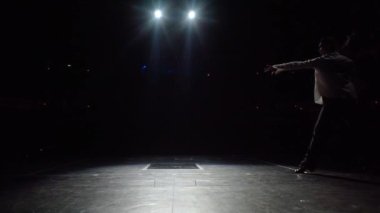 Dansçı çift sahnede karanlıktan çıkıyor, karanlık oditoryumun arka planında siluetler var. Tango ya da vals içinde çift dönüş, son anda donma, erkek kadını tutuyor, kadın başını geriye atıyor, kıvırıyor, güzel saçlar.