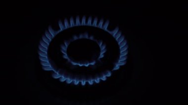 Yakından bakınca, gaz ocağı yanıyor ve siyah arka planda mutfaktaki gaz sobasının üzerine yavaşça sönüyor. Enerji krizi kavramı. Gaz kaynaklarının yok edilmesi. İnsanlar olmadan. Üst Manzara. 4K.