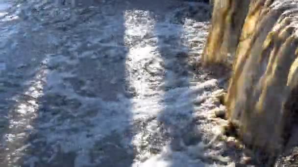 Špinavá bahnitá voda z kanálu teče jako vodopád do řeky za jasného slunečného dne. Detailní záběr. Koncept znečištění životního prostředí. 4K — Stock video