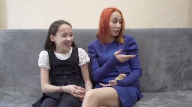 İki neşeli genç kız evcil hayvanlarla gülüp oynuyorlar: bir köpek, bir kedi ve bir fare, evde kanepede oturuyor. Yakın plan. 4K