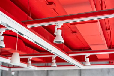 Tavan monte edilmiş kaset tipi havalandırma üniteleri ve havalandırma sisteminin diğer bölümleri (borular, kablolar ve havalandırmalar) ticari salonda asılı ışıklar ve diğer inşaat parçaları ile yerleştirildi..