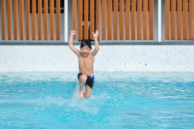 Asyalı genç adam havuzda iyi vakit geçiriyor, Yazın zıplıyor ve su oynuyor..