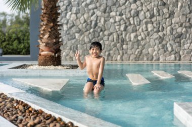 Asyalı genç adam havuzda iyi vakit geçiriyor, Yazın zıplıyor ve su oynuyor..