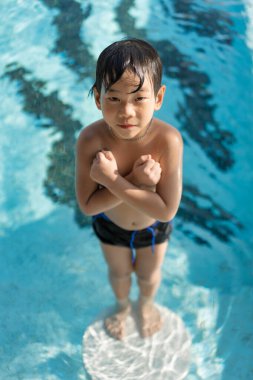 Asyalı genç adam havuzda iyi vakit geçiriyor, Yazın zıplıyor ve su oynuyor..
