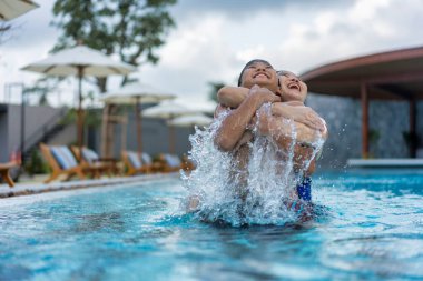 Asyalı Aile, Genç Oğlan ve 40 'lı yaşlardaki Kadın Anne Yüzme Havuzu' nda Eğleniyor ve Eğleniyor