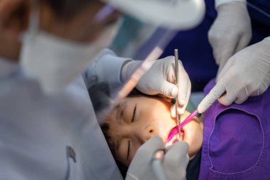 Doktor Dişçi 'nin eli, Asyalı küçük bir çocuğun dişleri üzerinde çalışıyor. 6 yaşındaki hasta diş hekiminde.