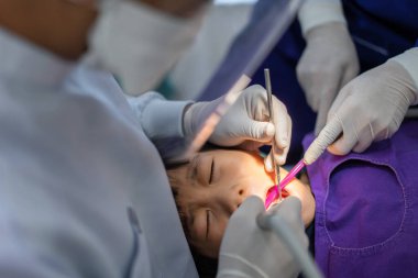Doktor Dişçi 'nin eli, Asyalı küçük bir çocuğun dişleri üzerinde çalışıyor. 6 yaşındaki hasta diş hekiminde.