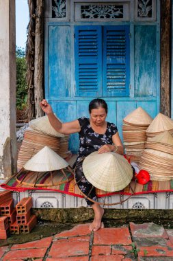 Yaşlı Vietnamlı kadın evinde geleneksel konik şapka yapıyor.