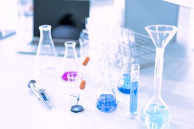 Mavi arka planda moleküler yapısı olan kimyasal bilim eğitim laboratuvarında cam matara.