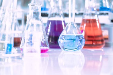 Mavi arka planda moleküler yapısı olan kimyasal bilim eğitim laboratuvarında cam matara.