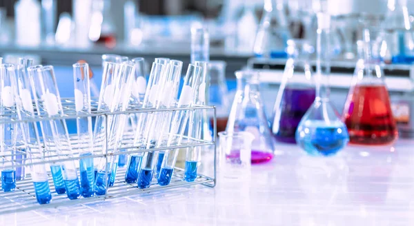 Mavi arka planda moleküler yapısı olan kimyasal bilim eğitim laboratuvarında cam matara.