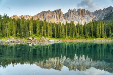 Italian alps. Silent morning on the lake of Carezza surrounded by pine forest and mountains.