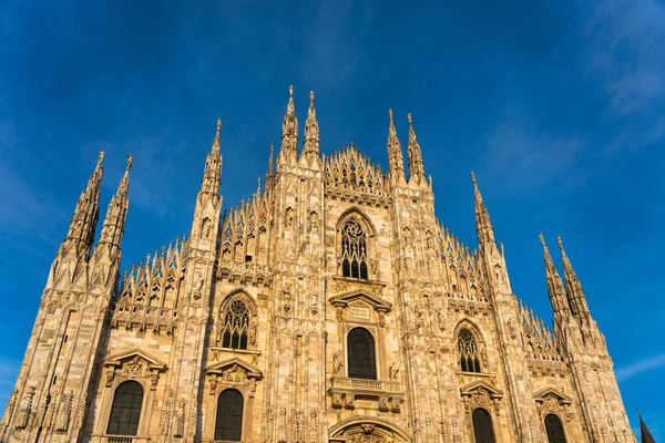 Sunset Scene of The ornate gothic facade, soaring spires and magnificent marble towers of the Duomo, Milan's monumental cathedral under big blue Lombardy skies