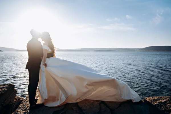 Beautiful wedding couple kissing on the background of sea. Beautiful wedding couple near the water. Love concept