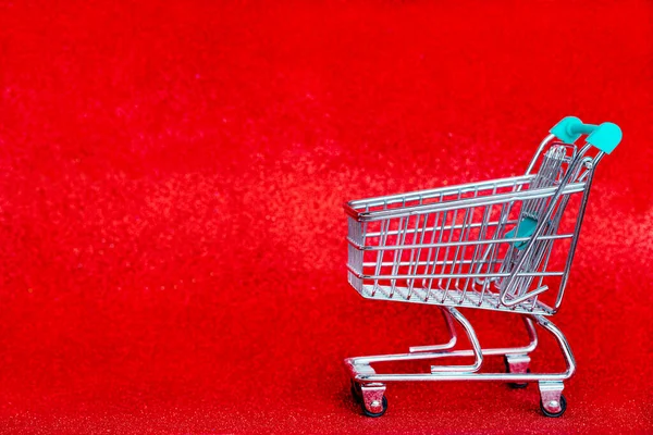 Troller de Natal em um fundo vermelho brilhante. Compras para o feriado. — Fotografia de Stock