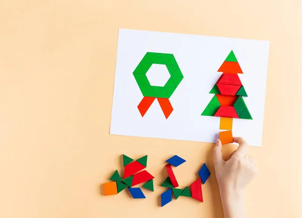 Ein Kind spielt mit farbigen Blöcken. Holzformen Weihnachtssymbole Weihnachtsbaum und -kranz — Stockfoto