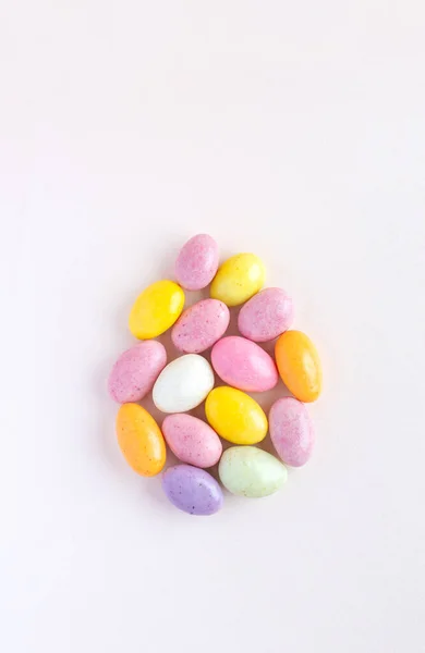 This Easter egg is made up of sweet colored chocolates. Delicate pastel pink background. — стоковое фото