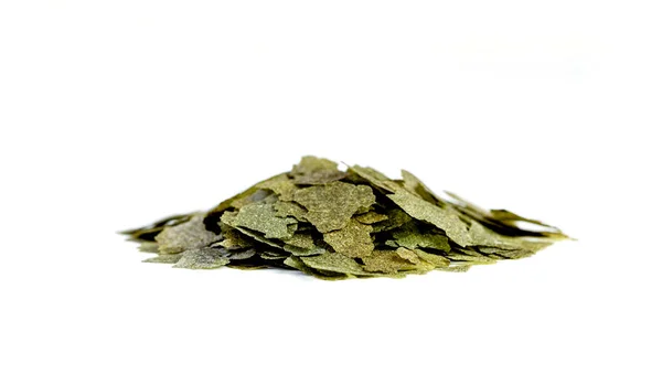 Dry handful, bunch green compound fish feed flakes on White background. Side view — Stockfoto