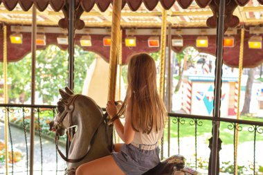 Castelnuovo del Garda, Italy - August 13 2019: Happy girl riding on carousel horse. Gardaland Theme Park in Castelnuovo Del Garda, Verona, Italy clipart