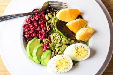 İçinde avokado, portakal, kabak tohumu, nar ve siyah pirinç bulunan Buda kasesi..