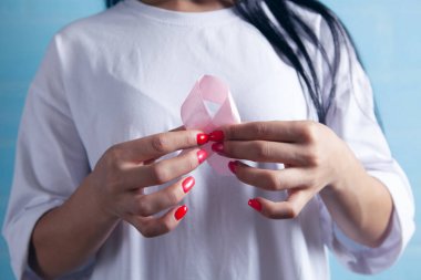 Genç kız pembe bir kurdele tutuyor.