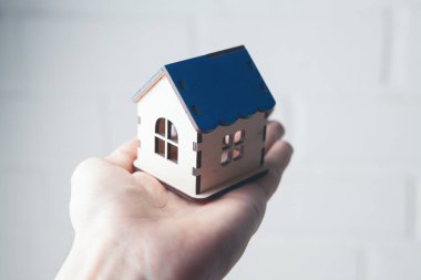 Beyaz arka planda bir evi tutan el.