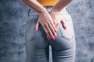 woman holding ass. hemorrhoids concept