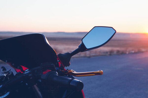 motorcycle stands on the road at sunset