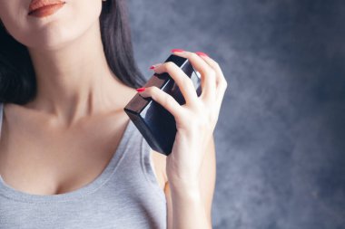 Kadın boynuna parfüm serpiyor.