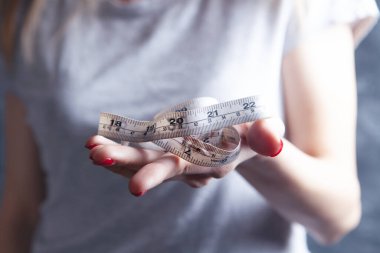 Genç kız elinde bir mezura tutuyor.