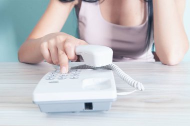 Bir kadın ev telefonundaki bir numarayı çevirir.