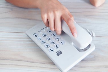 Bir kadın ev telefonundaki bir numarayı çevirir.