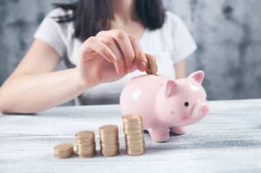 Bir kumbara ve bozuk para grafiğinin yanına bir bozuk para koyar.