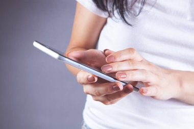 Genç bir kız elinde telefonla dikiliyor.