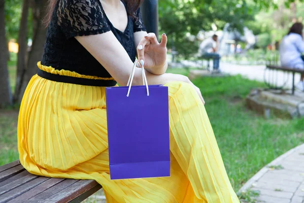 woman holding a gift bag while sitting on a bench