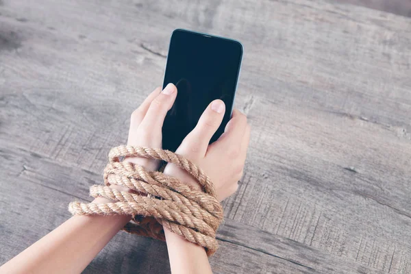 Bir iple bağlanmış kadın elleri telefonu tut.