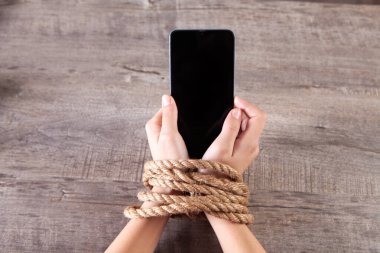 Bir iple bağlanmış kadın elleri telefonu tut.