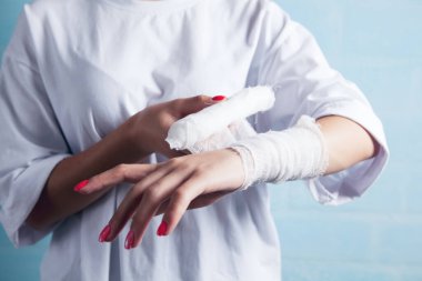 Genç kız elini bandajlıyor.