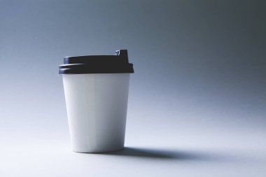 Gri arka planda tek kullanımlık kahve bardağı.