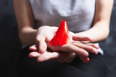 Genç bir kadın elinde kırmızı AIDS kurdelesi tutuyor.