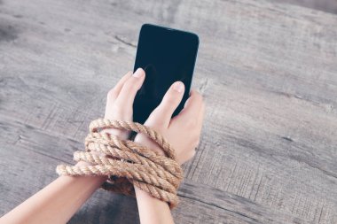 Bir iple bağlanmış kadın elleri telefonu tut.