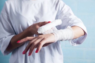 Genç kız elini bandajlıyor.