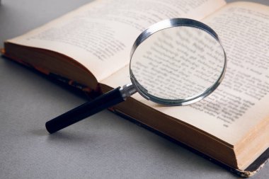 Masanın üzerinde bir kitap ve büyüteç var.