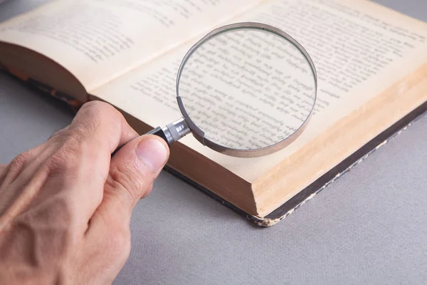 Büyüteçle bir kitaba bakıyorum.