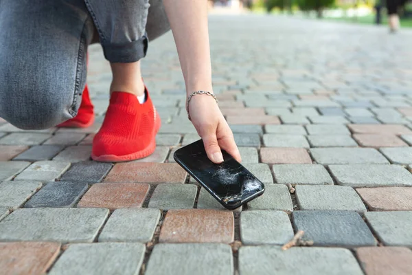 Bozuk bir telefonu yerden kaldırır.