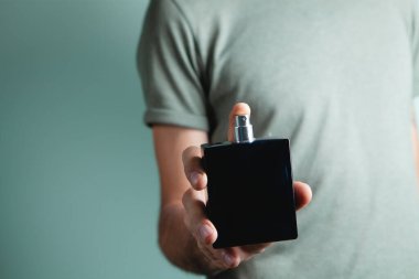 Elinde parfüm tutan genç bir adam.