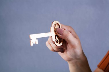 Gri arka planda ahşap anahtarlar tutan kadın.