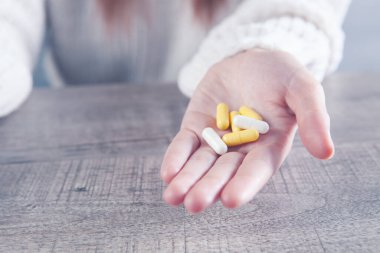 Elinde kapsüller tutan genç bir kadın.